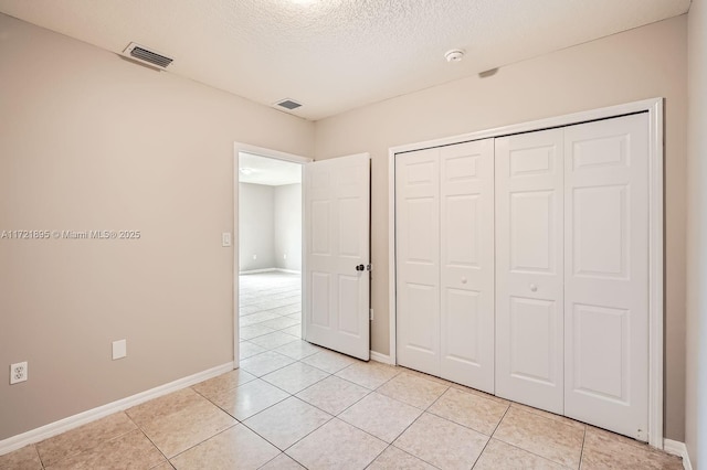 unfurnished bedroom featuring a closet, light tile patterned floors, and a textured ceiling