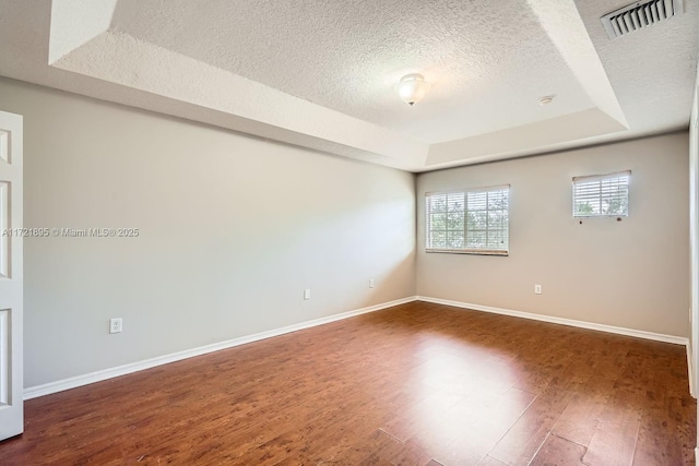 unfurnished room featuring a raised ceiling, a textured ceiling, and dark hardwood / wood-style flooring