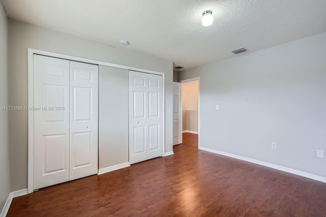 unfurnished bedroom featuring a textured ceiling and dark hardwood / wood-style floors