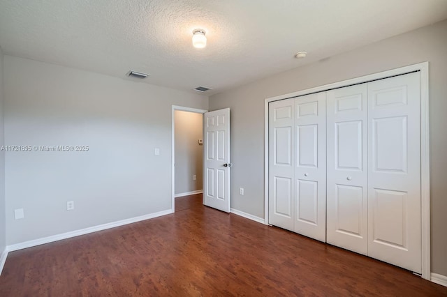 unfurnished bedroom with a closet, dark hardwood / wood-style floors, and a textured ceiling