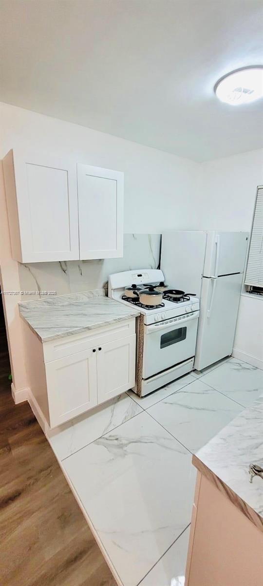 kitchen with white cabinetry and white appliances