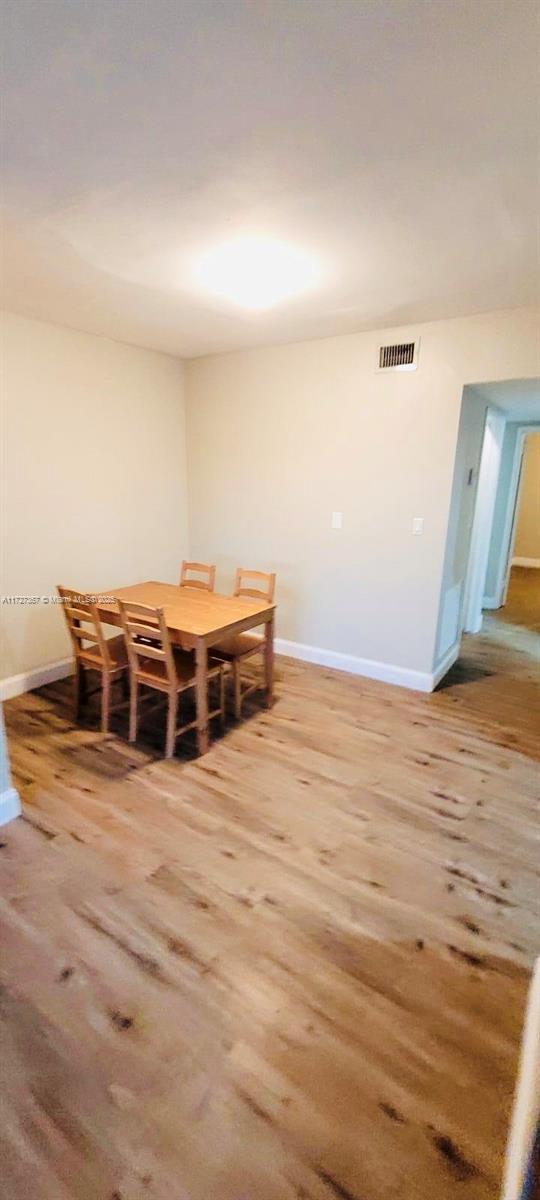 kitchen featuring dark wood-type flooring, stainless steel appliances, white cabinetry, and decorative light fixtures