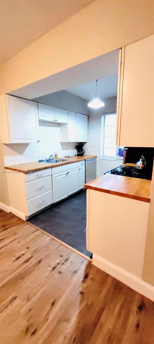 kitchen featuring stainless steel dishwasher, pendant lighting, white cabinets, and dark hardwood / wood-style floors