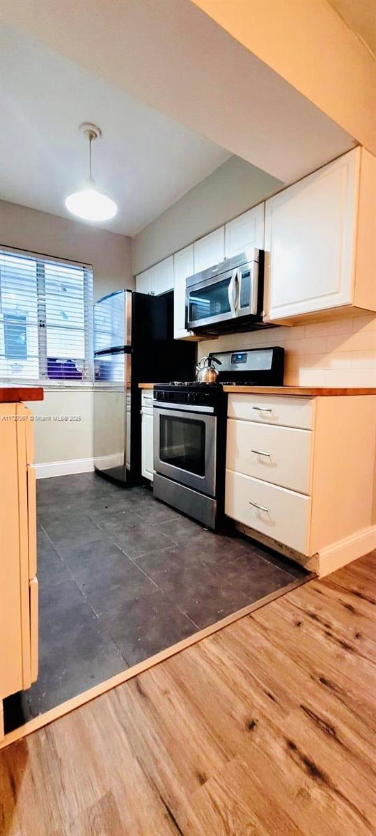 kitchen featuring white cabinets, pendant lighting, appliances with stainless steel finishes, and dark hardwood / wood-style floors