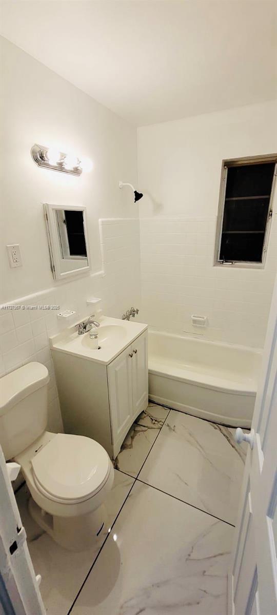 full bathroom with shower / bathtub combination, tile walls, toilet, and vanity