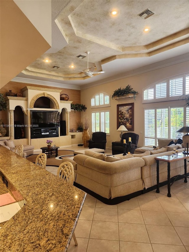 tiled living room featuring crown molding, a raised ceiling, and a healthy amount of sunlight