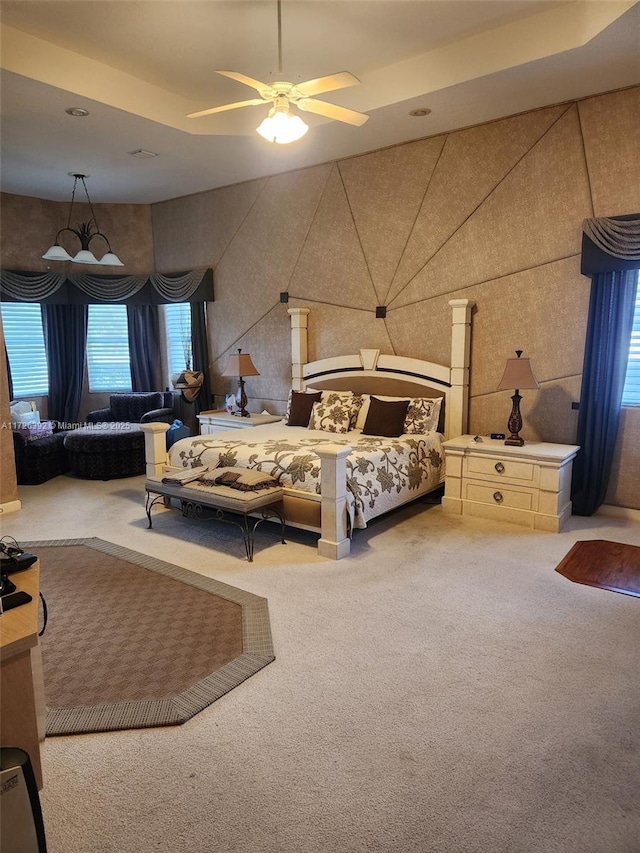 carpeted bedroom featuring ceiling fan and a tray ceiling