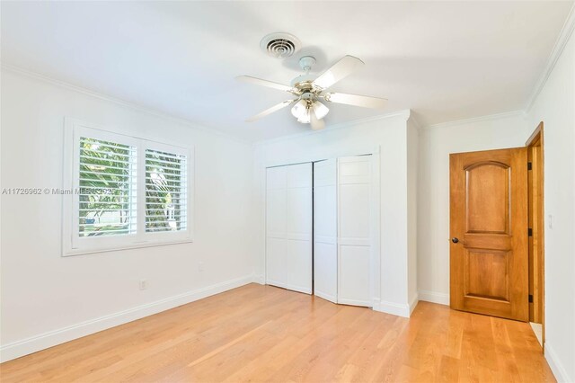 unfurnished bedroom featuring ceiling fan, a closet, crown molding, and light hardwood / wood-style flooring