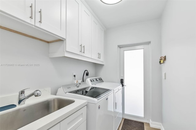 washroom featuring washer and dryer, sink, and cabinets