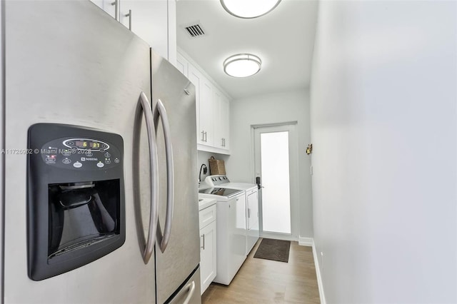 laundry area featuring light hardwood / wood-style flooring, washer and dryer, and cabinets