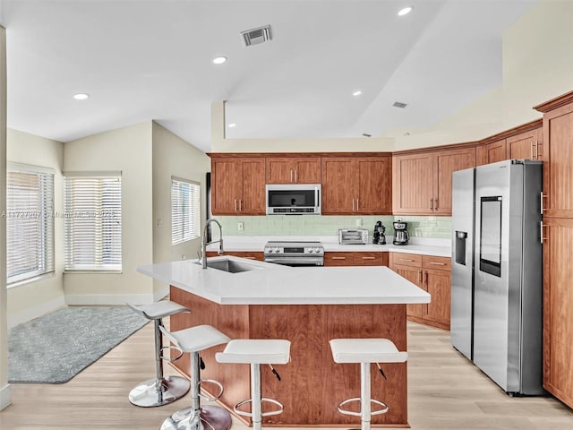 kitchen with stainless steel appliances, a breakfast bar area, sink, and a center island with sink