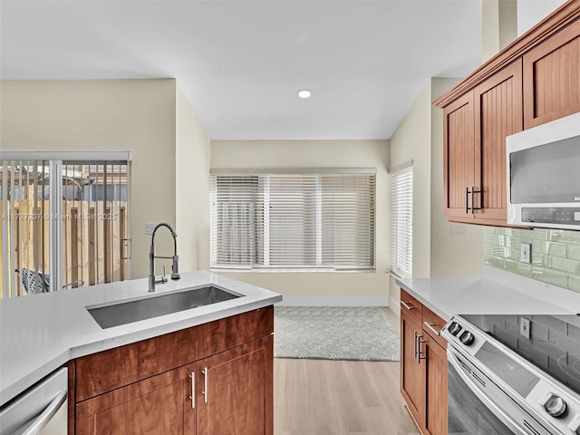 kitchen with tasteful backsplash, stainless steel appliances, light hardwood / wood-style floors, and sink