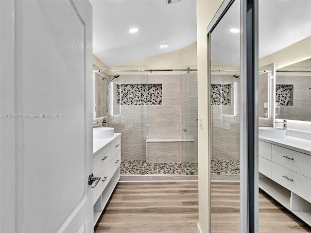 bathroom with vanity, hardwood / wood-style flooring, vaulted ceiling, and a shower with shower door