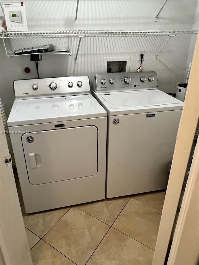 clothes washing area with light tile patterned floors and washer and clothes dryer