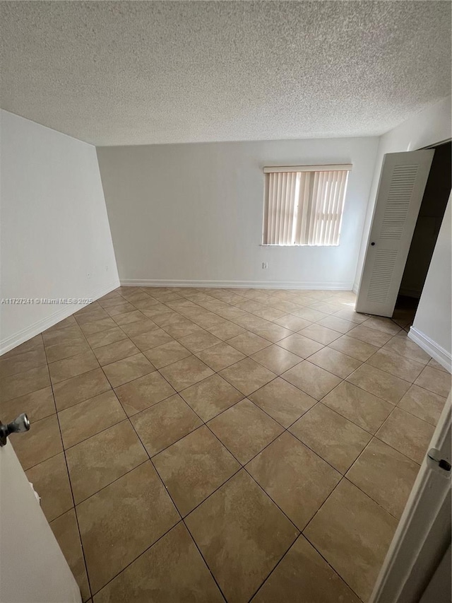 empty room featuring a textured ceiling and light tile patterned floors