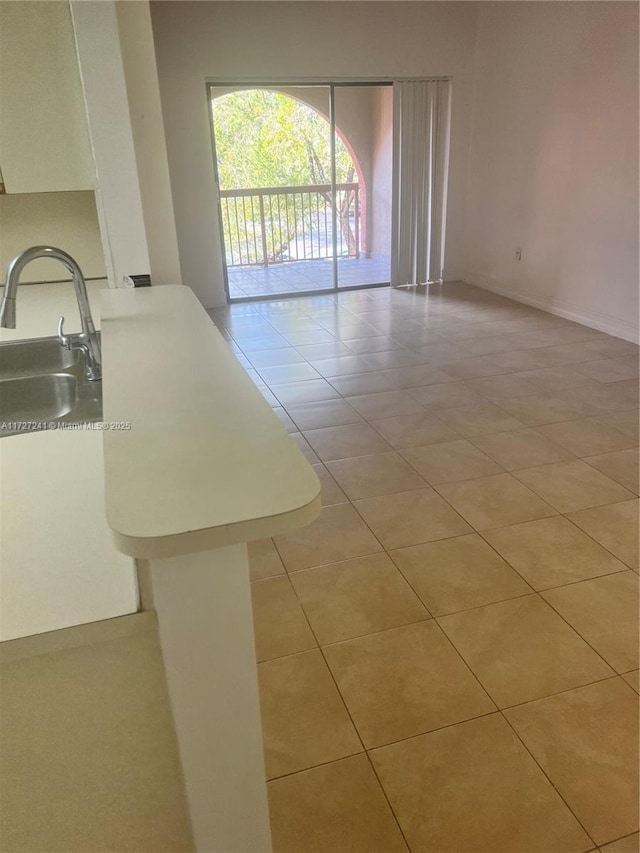 unfurnished living room featuring sink and light tile patterned floors