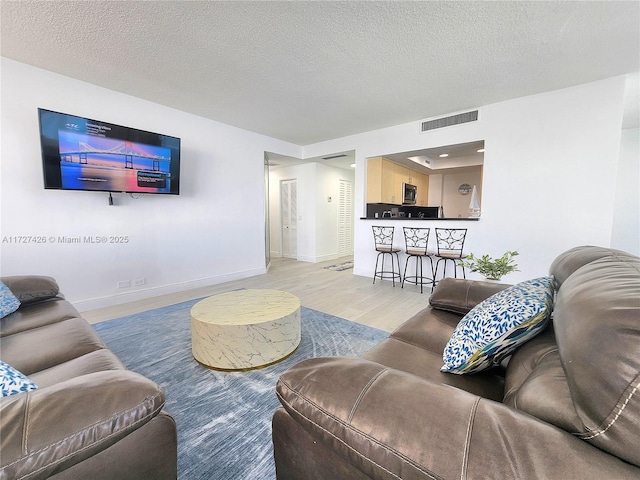 living room featuring a textured ceiling and light wood-type flooring