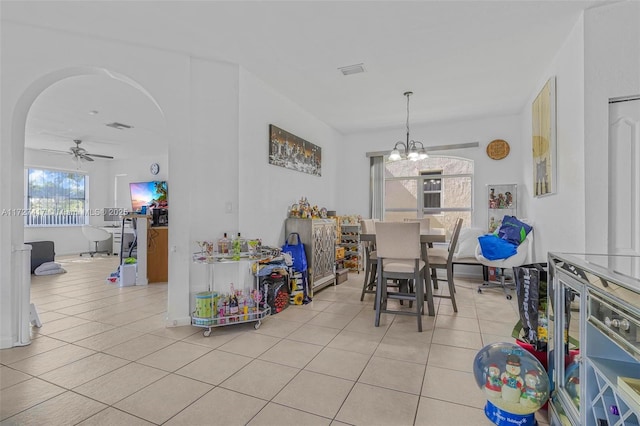 tiled dining room with ceiling fan with notable chandelier