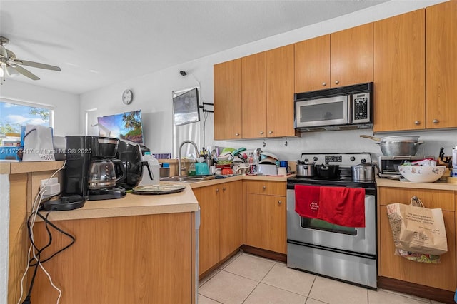 kitchen with appliances with stainless steel finishes, sink, light tile patterned floors, and ceiling fan