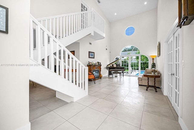 stairway featuring a towering ceiling, tile patterned floors, and french doors