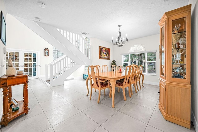 dining space with light tile patterned floors, a textured ceiling, a chandelier, and french doors