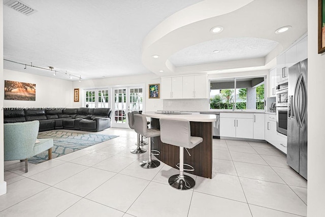 kitchen with sink, a breakfast bar area, appliances with stainless steel finishes, white cabinetry, and light tile patterned flooring