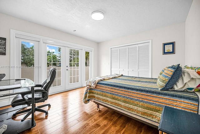 bedroom featuring wood-type flooring, a textured ceiling, french doors, access to outside, and a closet