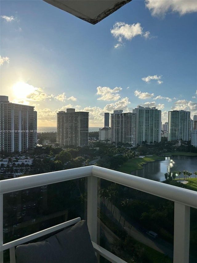 balcony at dusk featuring a water view