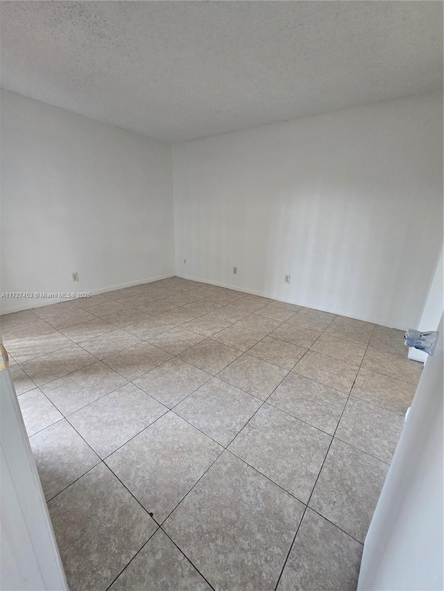 tiled spare room with a textured ceiling