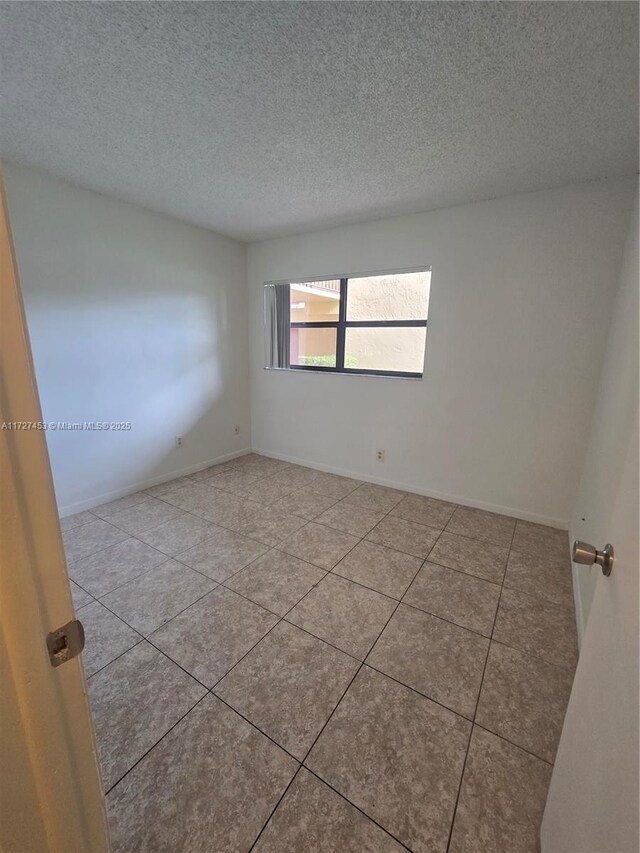 tiled spare room with a textured ceiling