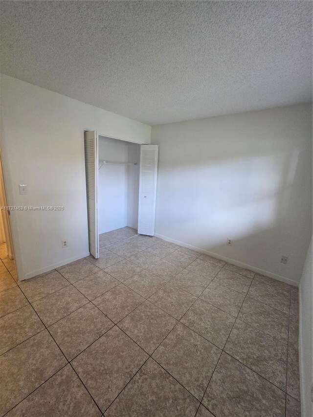 empty room with ceiling fan, tile patterned floors, and a textured ceiling