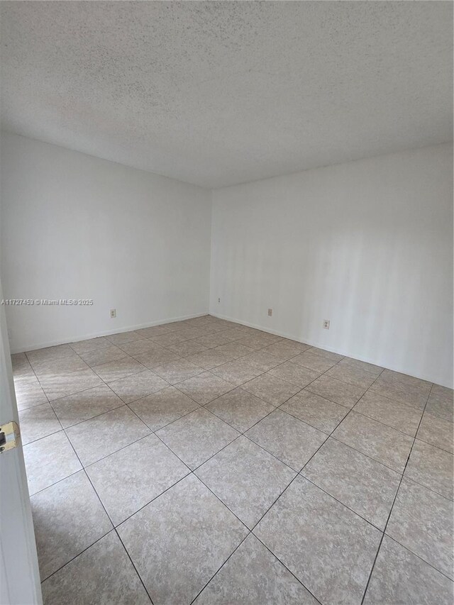 tiled spare room featuring a textured ceiling