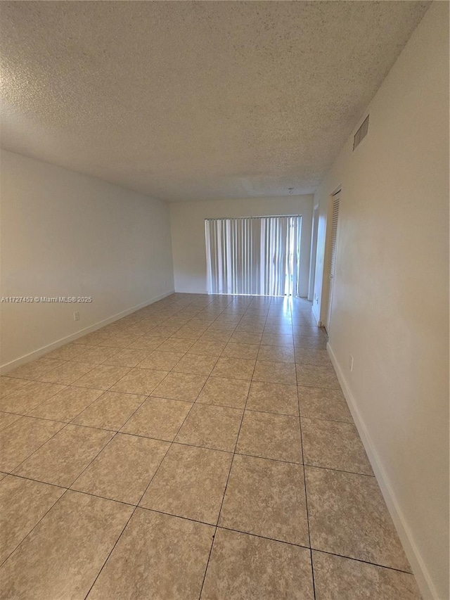 tiled empty room with a textured ceiling