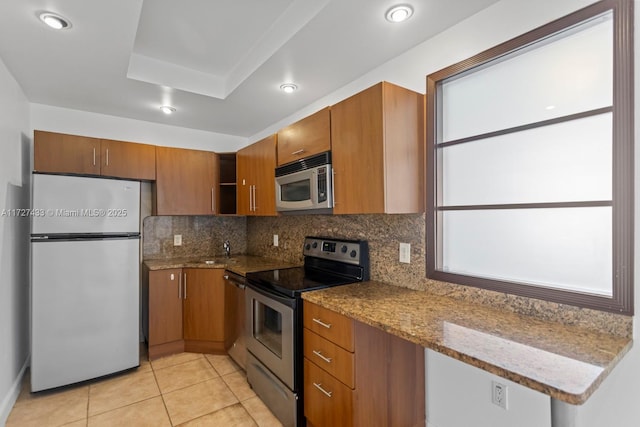 kitchen with sink, backsplash, light tile patterned floors, light stone counters, and stainless steel appliances