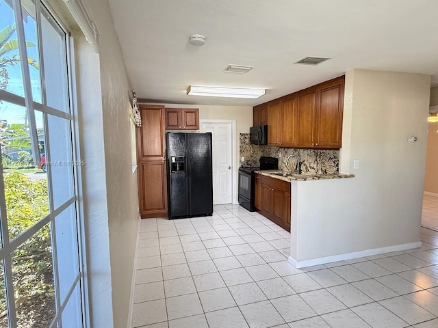 kitchen with backsplash, sink, light tile patterned floors, and black appliances