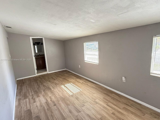 spare room featuring light hardwood / wood-style floors and a textured ceiling