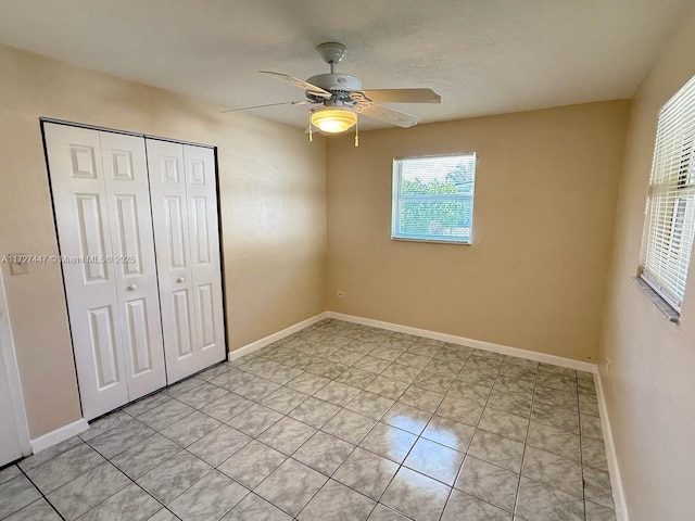 unfurnished bedroom with light tile patterned flooring, ceiling fan, and a closet