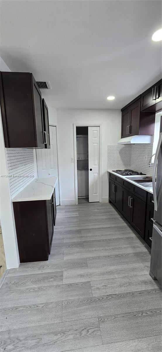 kitchen featuring light wood-style flooring, visible vents, dark brown cabinets, freestanding refrigerator, and decorative backsplash