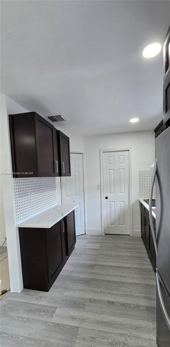 kitchen with tasteful backsplash, sink, stainless steel fridge, and light hardwood / wood-style flooring