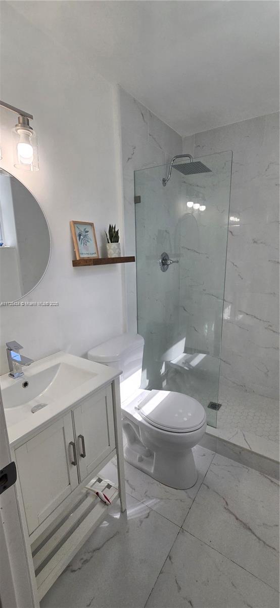 full bathroom with a marble finish shower, marble finish floor, vanity, and toilet