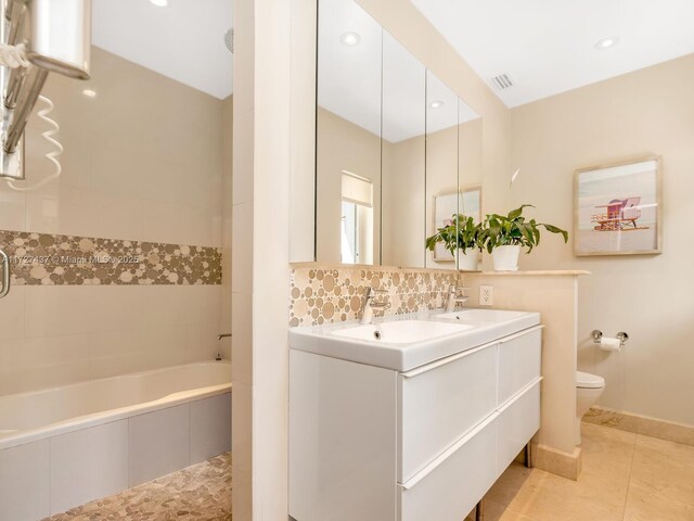 bathroom featuring toilet, tile patterned flooring, tiled tub, and vanity