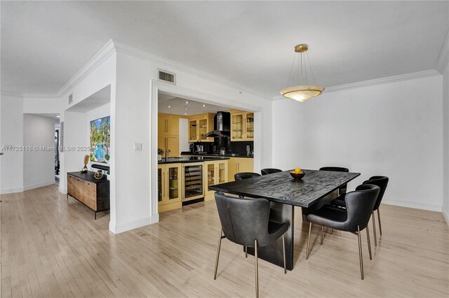 dining space with light wood-type flooring, ornamental molding, wine cooler, and sink