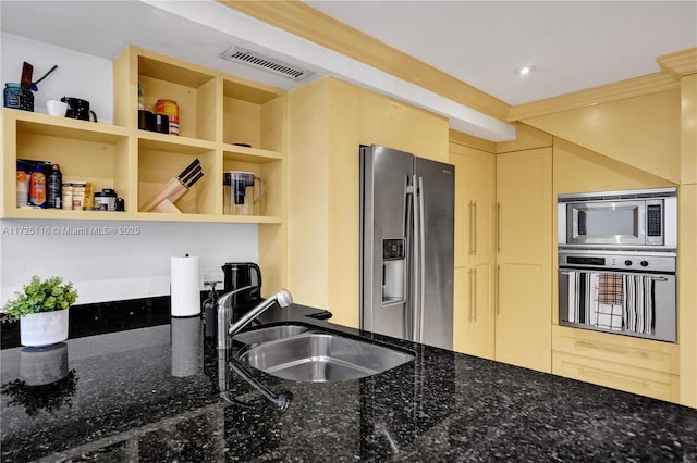 kitchen with sink, appliances with stainless steel finishes, crown molding, and dark stone countertops