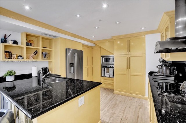 kitchen with light wood-type flooring, appliances with stainless steel finishes, dark stone countertops, and sink