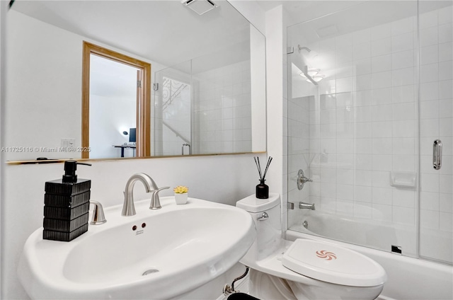 full bathroom featuring sink, bath / shower combo with glass door, and toilet