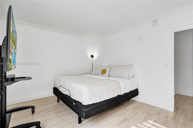 bedroom with ornamental molding and light hardwood / wood-style floors