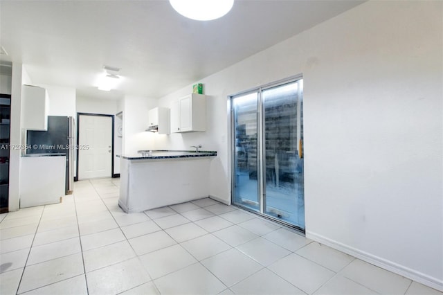 kitchen with white cabinets, kitchen peninsula, stainless steel fridge, and light tile patterned flooring