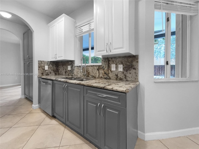 kitchen featuring light tile patterned floors, dishwasher, white cabinets, and sink