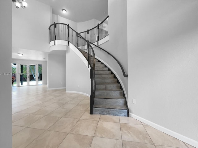 stairway featuring tile patterned flooring, a towering ceiling, and french doors