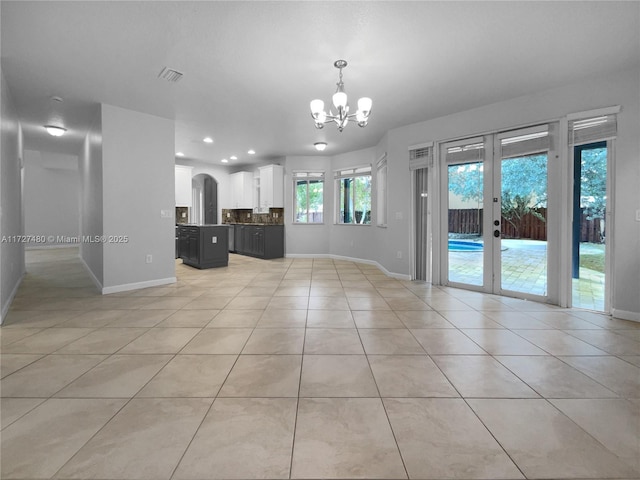 unfurnished living room with light tile patterned floors, a chandelier, and french doors